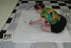 Caryl working on big drawing on floor of studio